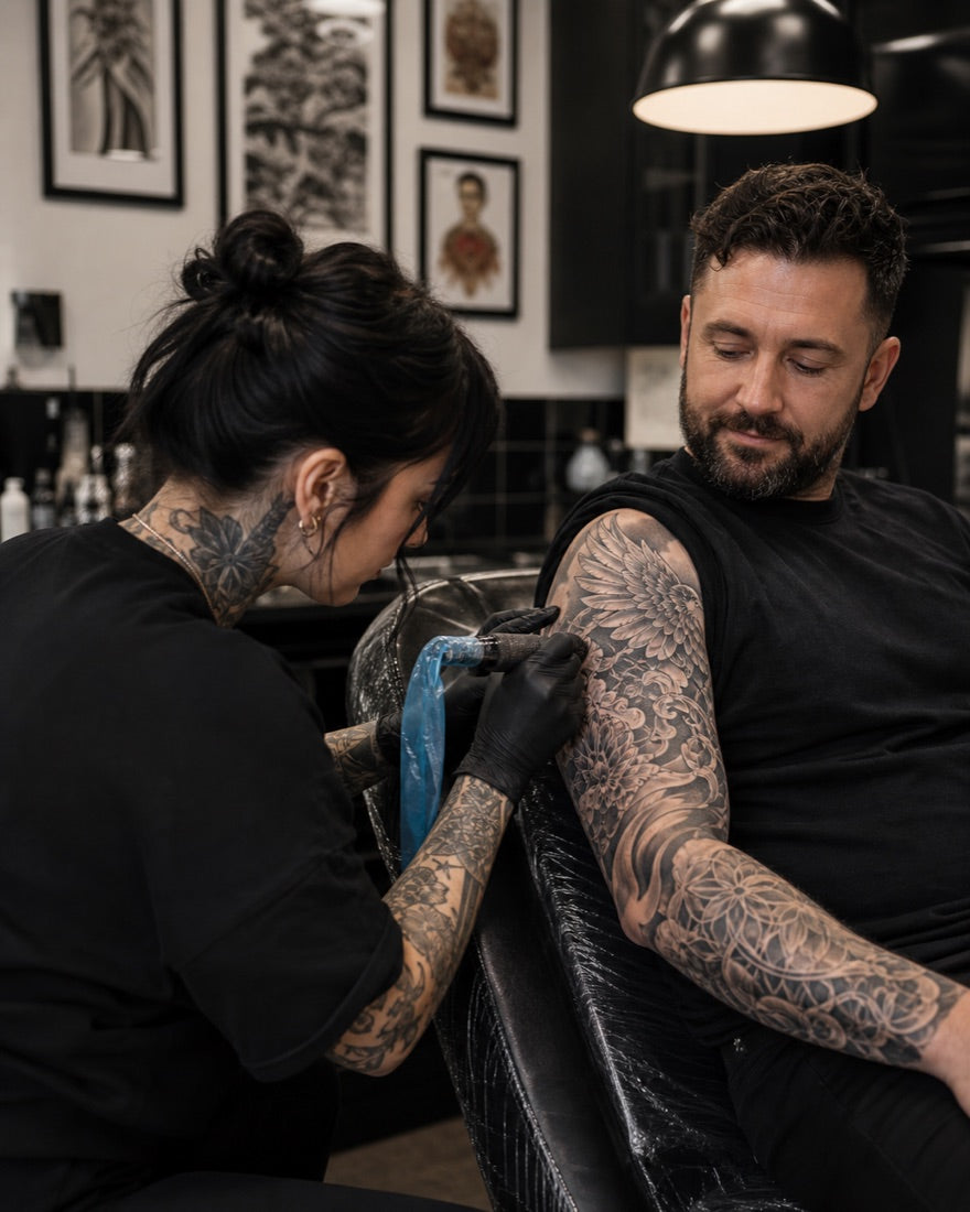 Tattoo artist tattooing a client's full sleeve